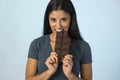 Young attractive and happy hispanic woman in blue top smiling excited eating chocolate bar background Royalty Free Stock Photo