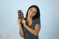 Young attractive and happy hispanic woman in blue top smiling excited eating chocolate bar background Royalty Free Stock Photo