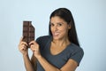 Young attractive and happy hispanic woman in blue top smiling excited eating chocolate bar background Royalty Free Stock Photo