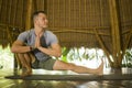 Young attractive and happy man doing yoga drill and stretching exercise smiling relaxed in harmony at beautiful Asian bamboo hut Royalty Free Stock Photo