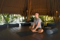 Young attractive and happy man doing yoga sitting in lotus position meditating relaxed in harmony at beautiful Asian bamboo hut Royalty Free Stock Photo