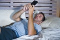 Young attractive and happy man lying on bed using internet mobile phone smiling sending text in social media and cellular communic Royalty Free Stock Photo