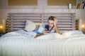 Young attractive and happy man lying on bed using internet mobile phone smiling sending text in social media and cellular communic Royalty Free Stock Photo