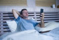 Young attractive and happy man lying on bed using internet mobile phone smiling sending text in social media and cellular communic Royalty Free Stock Photo