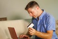 Young attractive and happy man relaxed at home sofa couch using credit card and laptop computer for internet shopping and banking Royalty Free Stock Photo