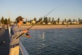 Young attractive and happy man in shirt and hat fishing at beach sea dock using fish road enjoying weekend hobby in holidays Royalty Free Stock Photo