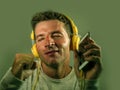 Young attractive and happy man smiling listening to internet music on headphones holding mobile phone dancing and singing groovy s Royalty Free Stock Photo