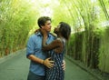 Young attractive and happy mixed ethnicity couple cuddling outdoors with attractive black afro American girfriend or wife and Royalty Free Stock Photo