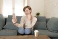 Young attractive and happy red hair woman sitting at home sofa couch drinking coffee taking selfie picture with mobile phone Royalty Free Stock Photo