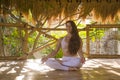 Young attractive and happy relaxed woman doing yoga and meditation exercise sitting in lotus position outdoors at wooden hut