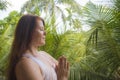 Young attractive and happy relaxed woman doing yoga and meditation exercise sitting in lotus position outdoors at wooden hut