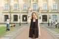 Young attractive happy student girl posing near the university building touching her head with her hand. Beautiful smiling female Royalty Free Stock Photo