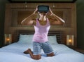 Young attractive and happy teen girl on bed playing with VR virtual reality goggles video game having fun excited and surprised Royalty Free Stock Photo