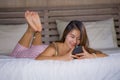 Young attractive and happy teenager woman lying relaxed and smiling cheerful in bed using internet social media or online dating Royalty Free Stock Photo