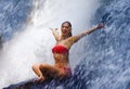 Young attractive and happy woman with fit body practicing yoga wet under tropical paradise waterfall stream screaming excited with Royalty Free Stock Photo