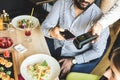 Young attractive Hindu man paying in cafe with contactless smartphone payment Royalty Free Stock Photo