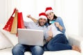 Young attractive Hispanic couple in love online Christmas shopping with computer Royalty Free Stock Photo