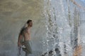 Young, attractive and Hispanic man, shirtless and with a muscular body, leaning against a wall under a bridge where a waterfall