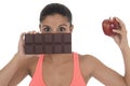 Young attractive hispanic woman in fitness top holding apple fruit and chocolate bar in her hands Royalty Free Stock Photo