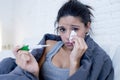 Young attractive hispanic woman lying sick at home couch in cold and flu in gripe disease symptom