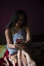 Young Indian brunette woman in sleeping wear sitting on a bed Royalty Free Stock Photo