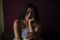 Young Indian brunette woman in sleeping wear sitting on a bed Royalty Free Stock Photo