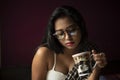 Young Indian brunette woman in white sleeping wear reading book on a bed Royalty Free Stock Photo