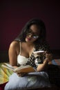 Young Indian brunette woman in white sleeping wear reading book on a bed Royalty Free Stock Photo