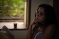 Young Indian brunette woman in white sleeping wear reading book on a bed Royalty Free Stock Photo