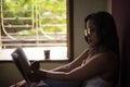 Young Indian brunette woman in white sleeping wear reading book on a bed Royalty Free Stock Photo