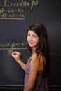 Showing her methodology. A young attractive Indian woman, solving a maths problem on the blackboard in class. Royalty Free Stock Photo