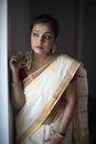 Portrait of an young and attractive Indian woman in white traditional wear for the celebration of Onam/Pongal Royalty Free Stock Photo