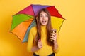 Young attractive lady with astonished facial expression posing with multicolored umbrella and coffee to go, stands with opened Royalty Free Stock Photo
