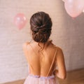 A young attractive lady, a peach dress with a purple color, shows a bare open back and a great neat dark hair hairstyle