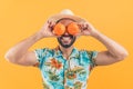 young attractive Latin American man laughing and putting oranges on eyes studio shot medium closeup orange background Royalty Free Stock Photo