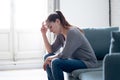 Young woman suffering from depression feeling sad and lonely on sofa at home