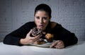 Young attractive latin woman sitting at table eating dish full of junk sugary unhealthy food Royalty Free Stock Photo