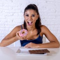 Portrait of young happy woman eating delighted chocolate bar and donuts Royalty Free Stock Photo