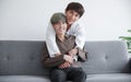 Young attractive LGBT gay couple smiling and hugging from back while they looking at camera and sitting on sofa at home Royalty Free Stock Photo