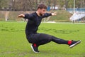 young attractive man athlete make squat on one leg at the stadium