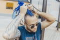 Young attractive man with blue dreadlocks touching his hair. Royalty Free Stock Photo