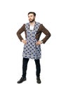 Young attractive man in a businessman suit and home apron for cleaning, put his hands on his hips. Royalty Free Stock Photo