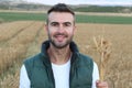 Young attractive man carrying bunch of ripe wheat