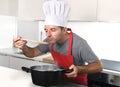 Young attractive man in chef hat and red cook apron testing flavor