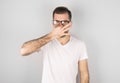 Young attractive man with disgust on his face pinches nose  something stinks  on gray background. Negative emotion facial Royalty Free Stock Photo