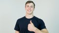 Young attractive man dressed in black t-shirt standing over white background looking at camera and showing thumb up Royalty Free Stock Photo