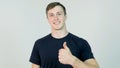 Young attractive man dressed in black t-shirt standing over white background looking at camera and showing thumb up Royalty Free Stock Photo