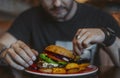 Young attractive man eating burger and french fries at cafe. Royalty Free Stock Photo