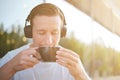 Young attractive man enjoying a cup of aromatic coffee outdoors in sunny weather