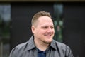 Young man in a black leather jacket and slicked back hair looking friendly to the side